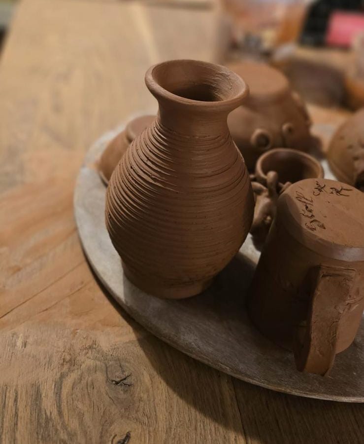 Petit vase en terre cuite aux stries régulières, posé sur un plateau