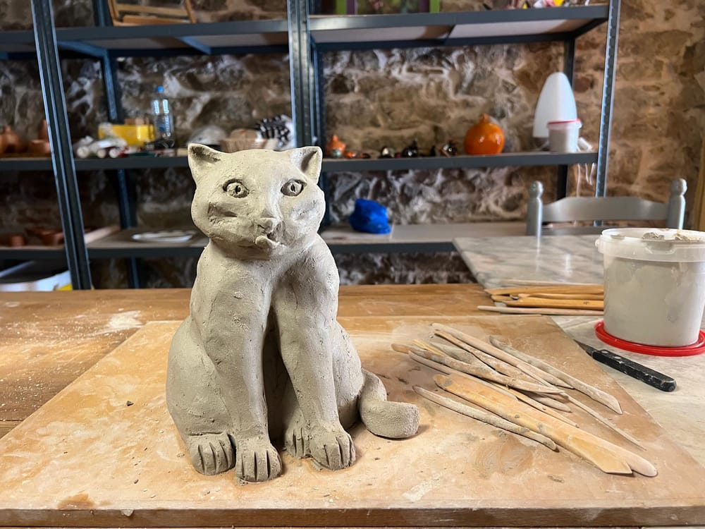 Chat en argile modelé à la main, entouré d'outils de sculpture